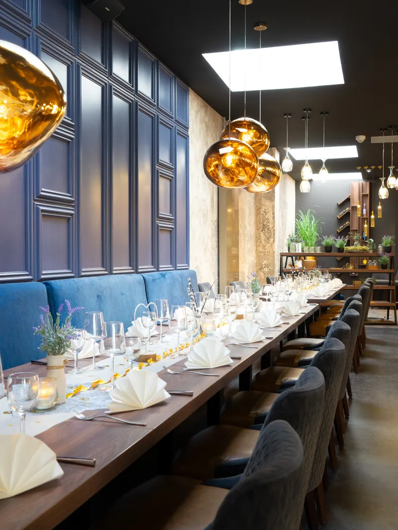 Festlich gedeckte lange Tafel mit blauen Wänden und goldenen Lampen