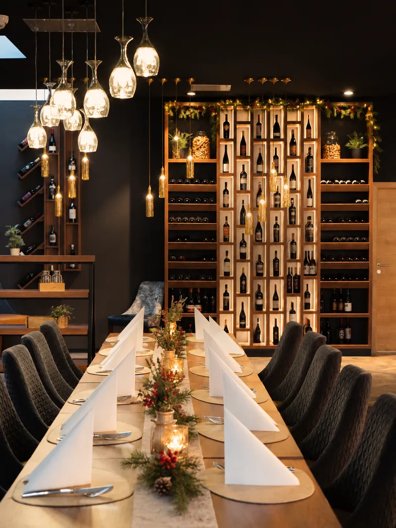 Weihnachtlich gedeckte lange Tafel in der Weinbar des Restaurants Schöne Momente in Brake, mit Kerzen, Tannenzweigen und beleuchteter Weinwand