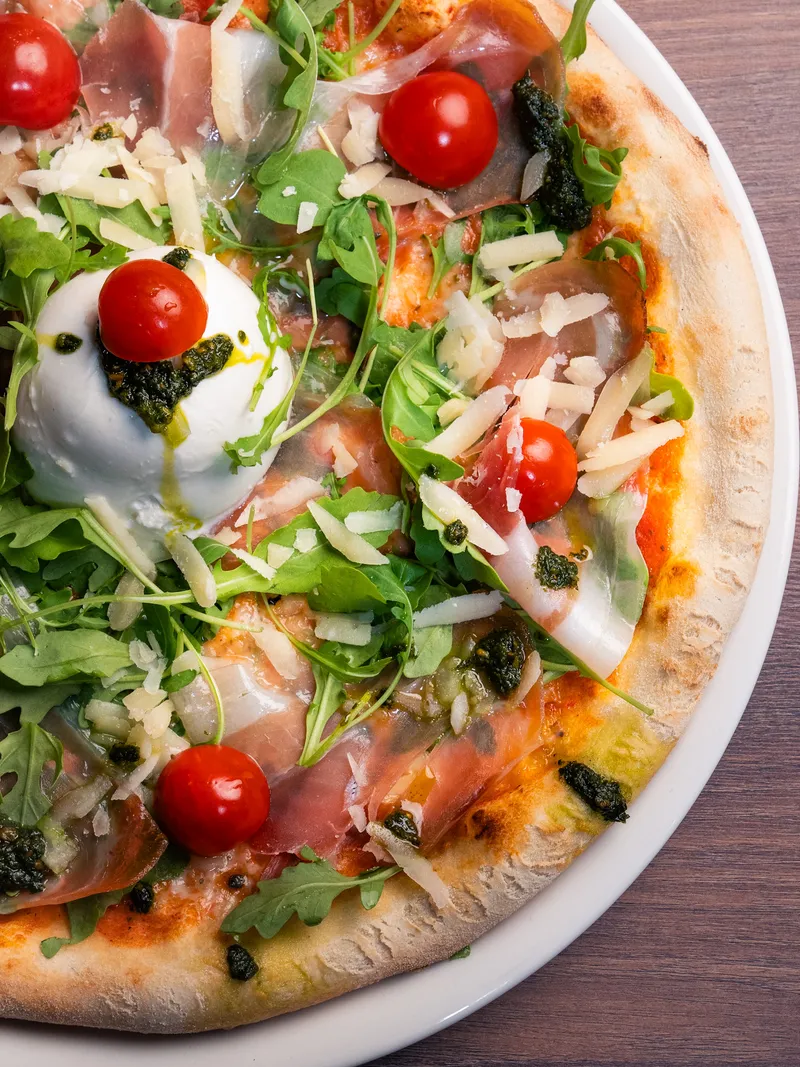 Pizza Delizia mit Burrata, luftgetrocknetem Schinken, Rucola und Cherrytomaten