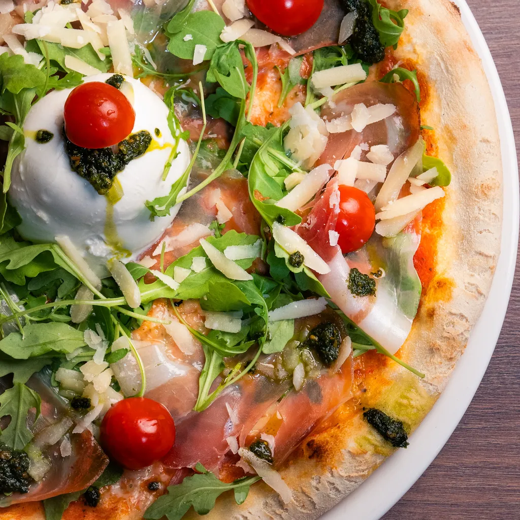Pizza Delizia mit Burrata, luftgetrocknetem Schinken, Rucola und Cherrytomaten