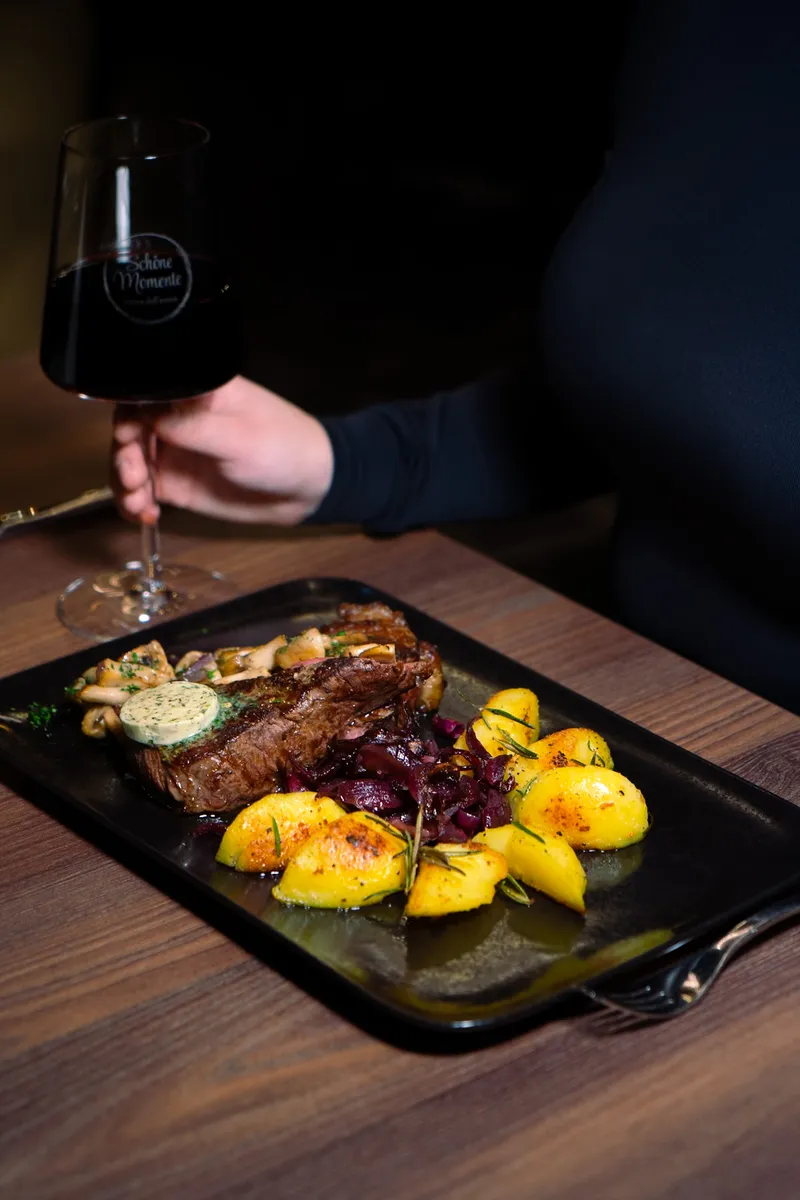 Steak mit Rotweinzwiebeln und Rosmarinkartoffeln, dazu ein Glas Rotwein